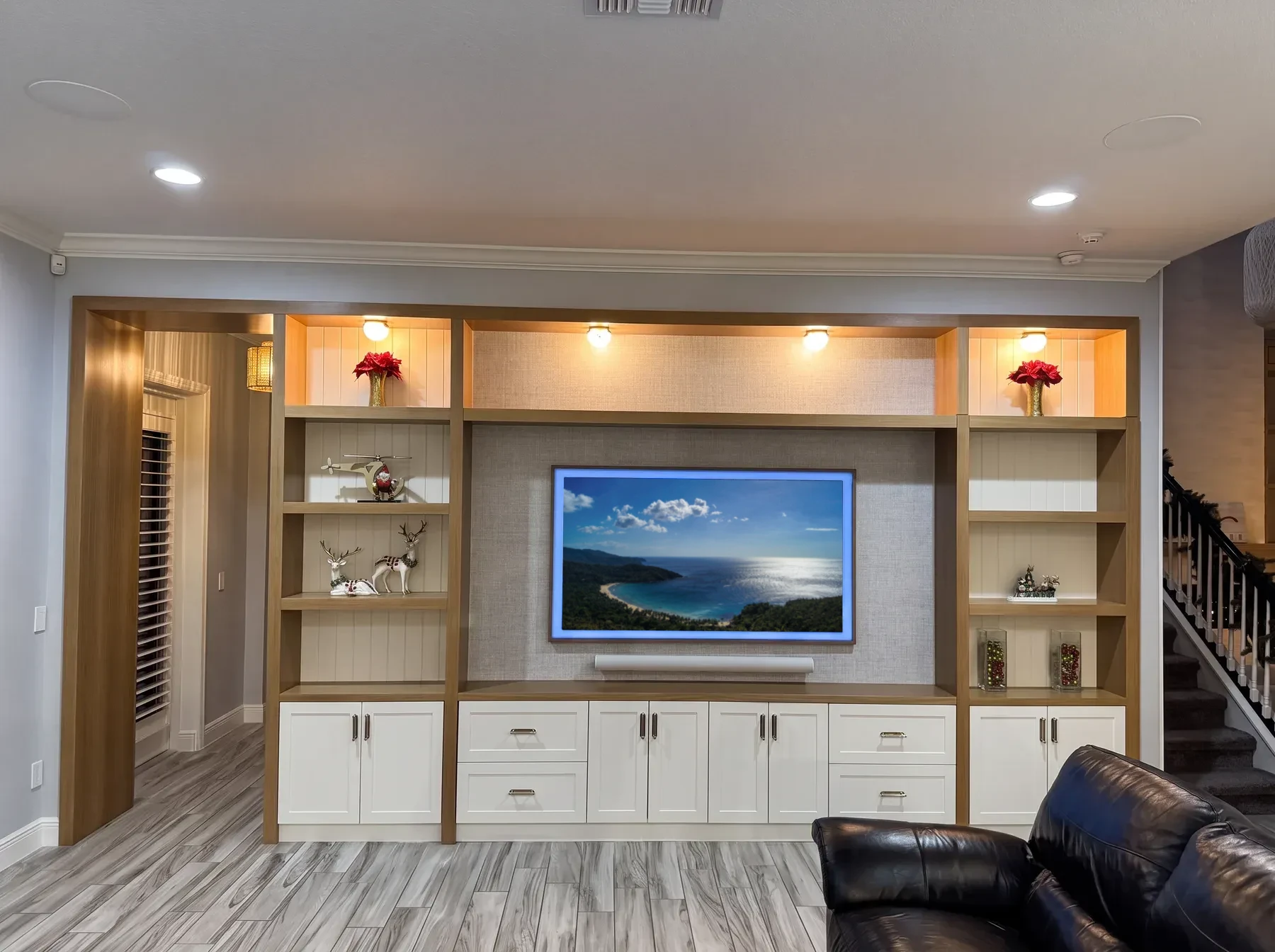 Full-wall white oak and painted entertainment built-in with a fabric-panel television surround and lit display shelves