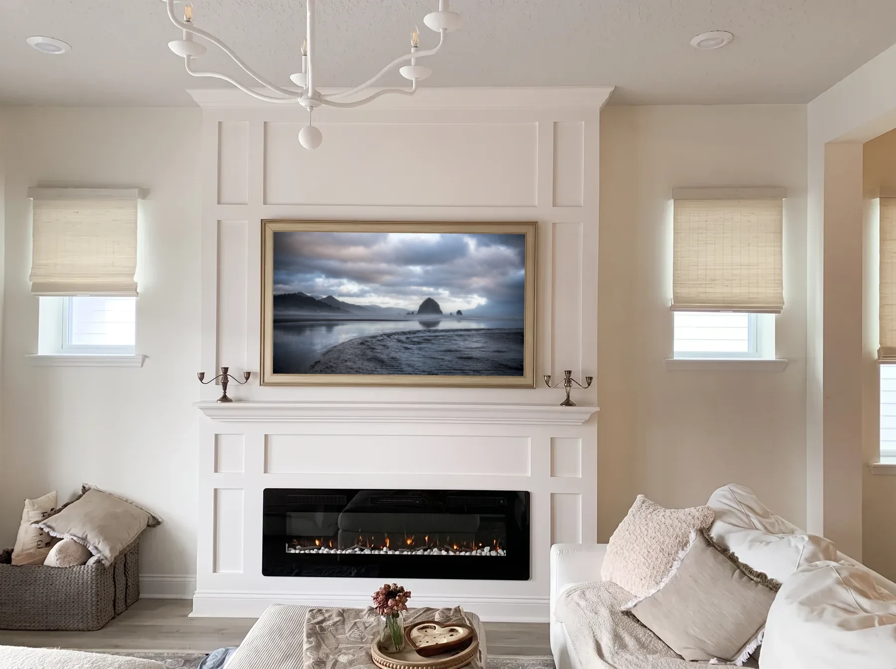 White painted millwork fireplace wall with a mantel shelf, framed-art television and linear fireplace