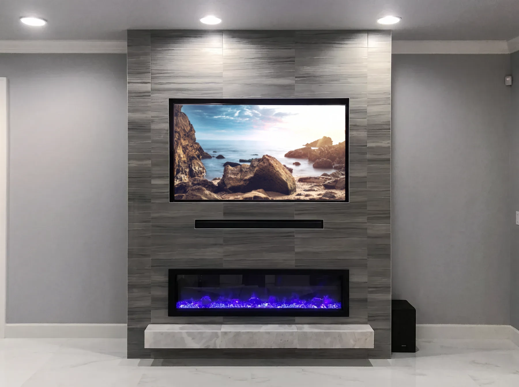 Grey vertical-grain porcelain tile wall with a floating stone hearth, linear fireplace and flush television