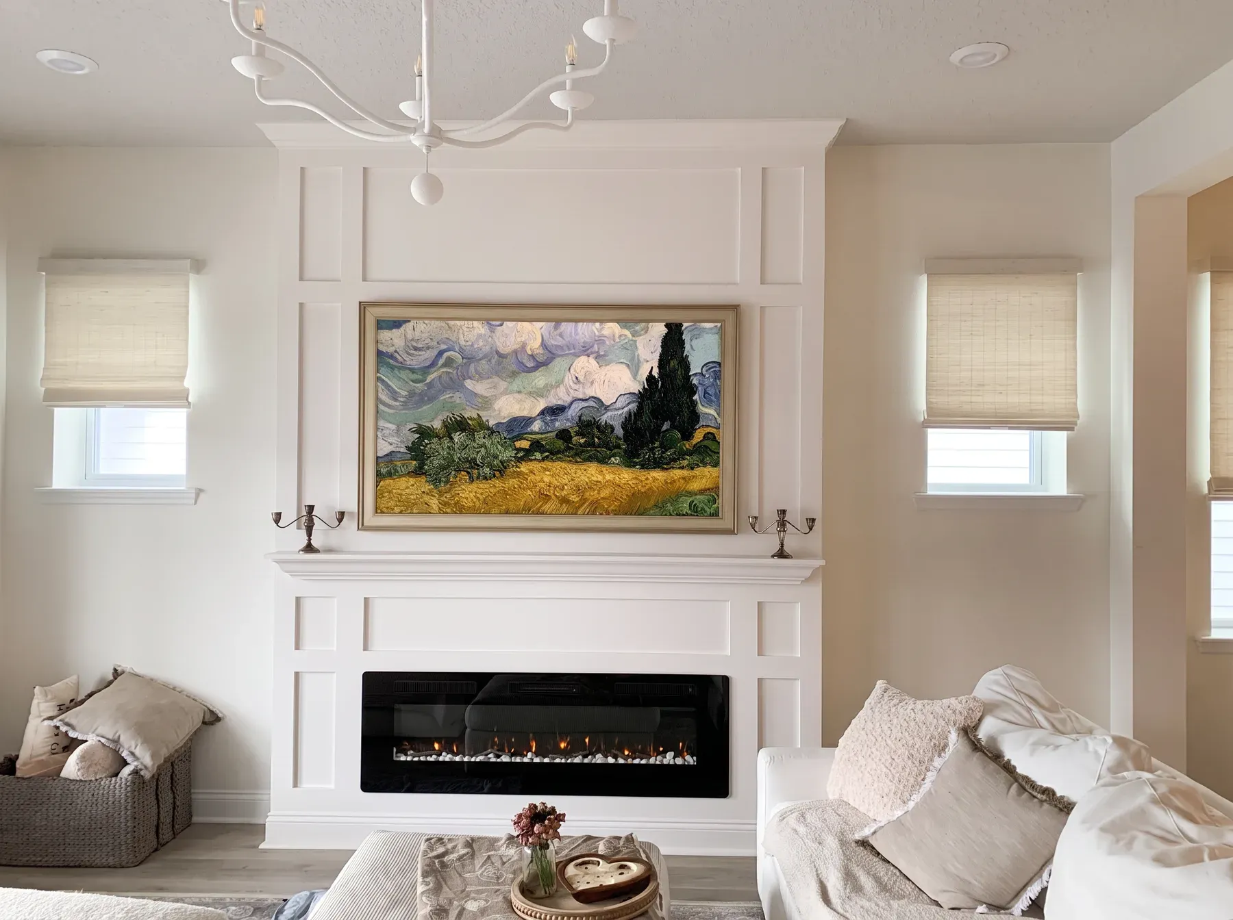 White painted millwork fireplace wall with a mantel shelf, framed-art television and linear fireplace